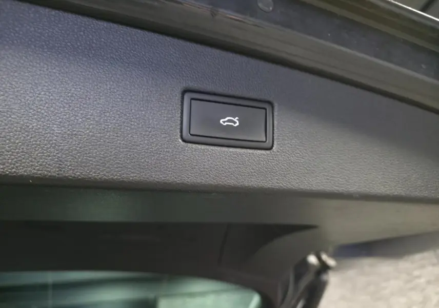 Bouton d'ouverture électrique du coffre sur le panneau intérieur gris du hayon d'un Volkswagen Tiguan 2022.