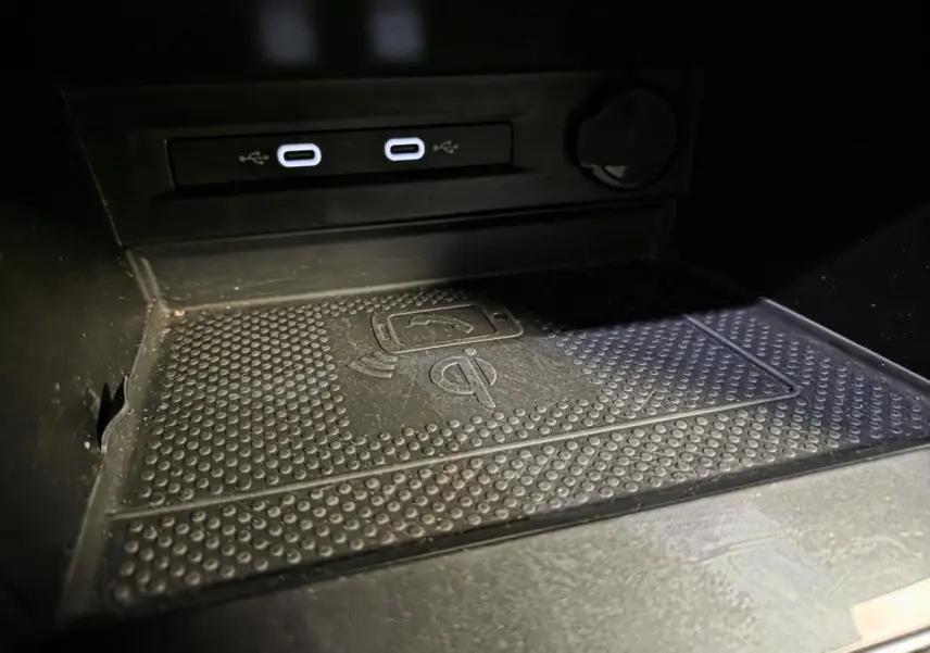 Gros plan sur la zone de recharge sans fil et les deux ports USB-C du Volkswagen Tiguan gris, intérieur noir.