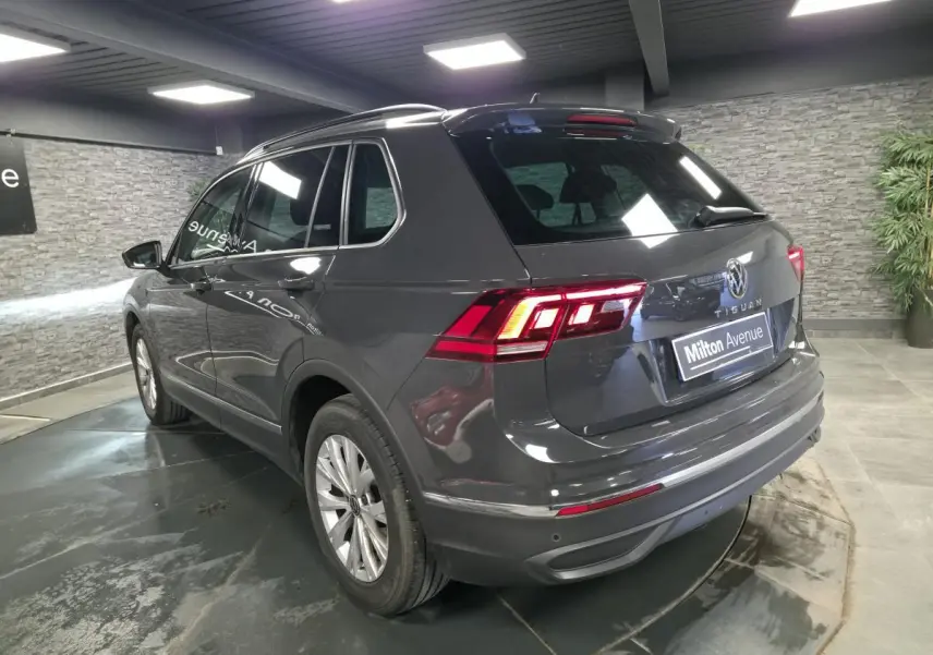 Volkswagen Tiguan gris 3/4 arrière droit en intérieur, feux arrière LED allumés et jantes alliage 17 pouces.