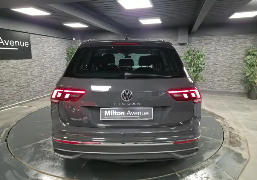 Vue arrière d'un Volkswagen Tiguan gris métallisé 2022 avec feux LED allumés dans un showroom.