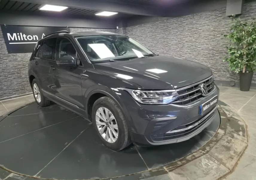 Volkswagen Tiguan gris 3/4 avant droit en intérieur, avec jantes alliage et calandre chromée.