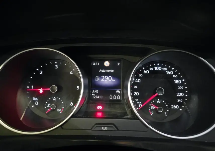 Vue rapprochée du tableau de bord du Volkswagen Tiguan gris, affichant l'autonomie et les compteurs analogiques.