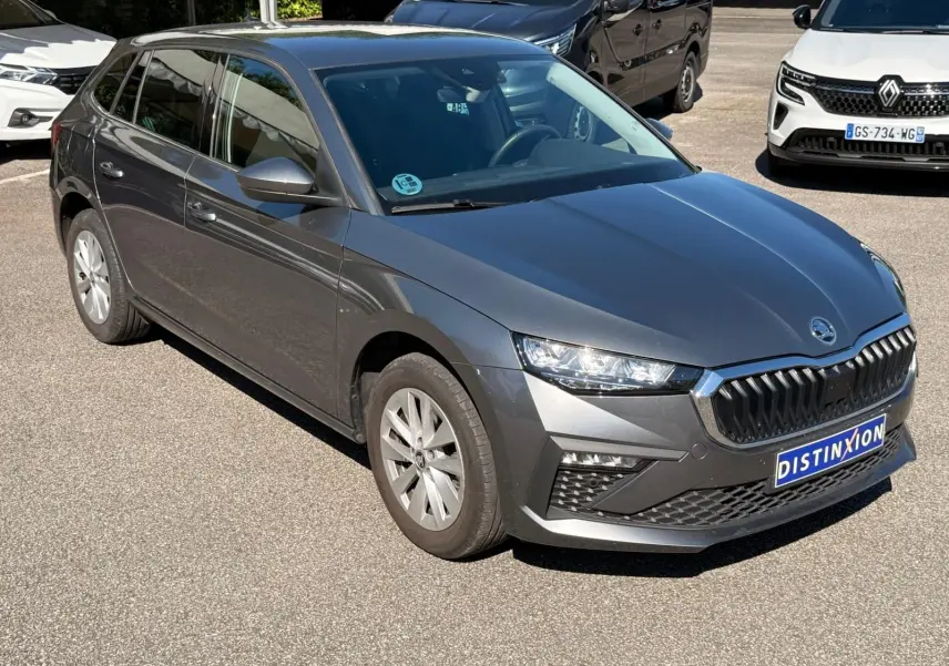 Vue 3/4 avant gauche d'une Skoda Scala gris graphite 2025 avec calandre distinctive et phares LED allumés.