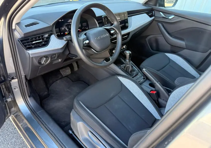 Intérieur avant droit d’une Skoda Scala gris graphite 2025, volant multifonction, sièges tissu bicolore et boîte auto DSG7.