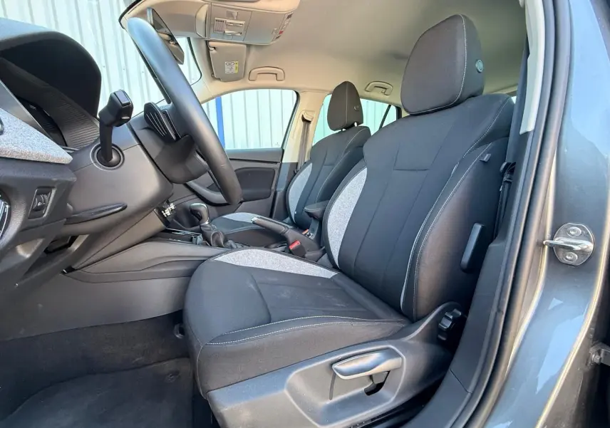 Vue intérieure côté conducteur de la Skoda Scala gris graphite 2025, montrant les sièges avant en tissu bicolore noir et gris.