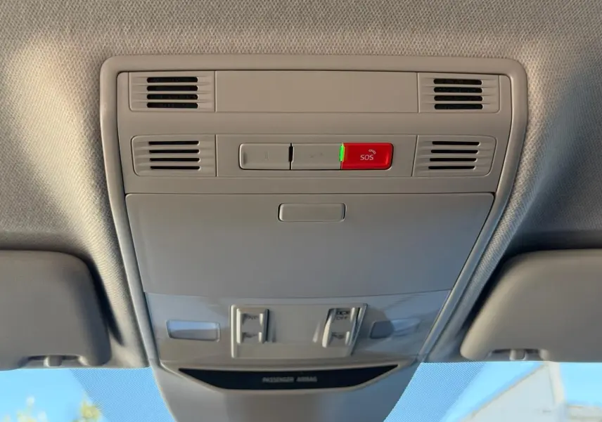 Plafonnier intérieur gris clair avec bouton SOS rouge et aérateurs, vue en contre-plongée depuis l'habitacle.