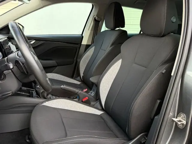 Vue intérieure côté conducteur de la Skoda Scala 2025, sièges tissu bicolore gris et noir, volant multifonction visible.
