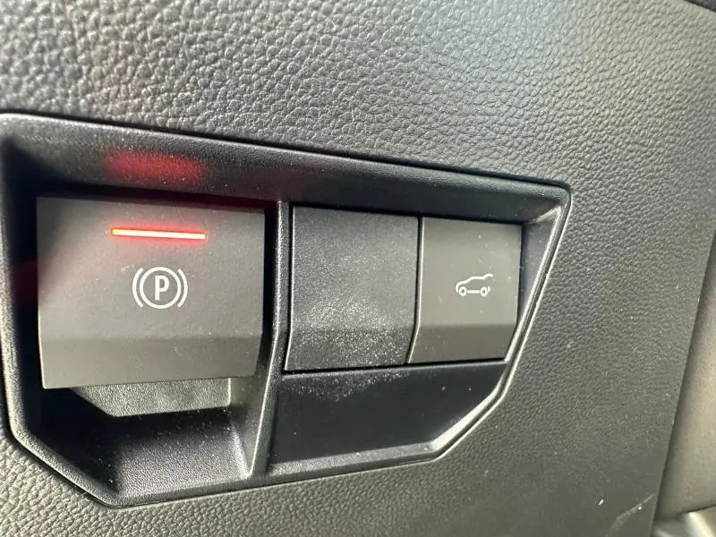 Gros plan sur les boutons de commande noirs du tableau de bord du Dacia Bigster, avec témoin rouge allumé.