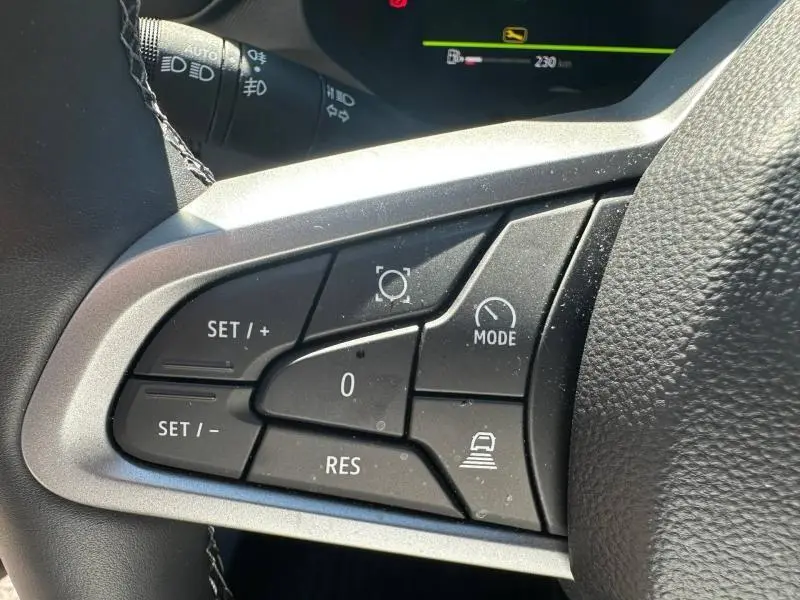 Gros plan sur les commandes multifonctions à gauche du volant du Dacia Bigster gris schiste, avec boutons de régulateur de vitesse et mode conduite.