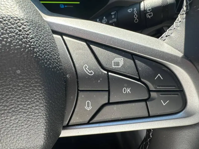 Gros plan sur les commandes multifonctions noires côté droit du volant du Dacia Bigster gris Schiste, avec boutons appel et navigation.