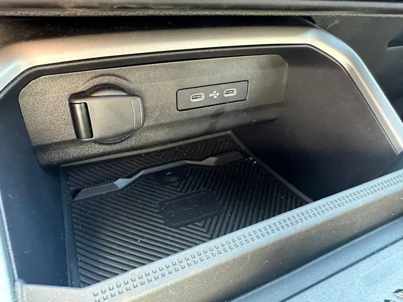 Gros plan sur la console centrale noire du Dacia Bigster 1.8 hybrid, montrant prises USB et prise 12V intégrées.