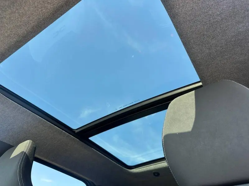 Toit panoramique en verre vu de l'intérieur du Dacia Bigster gris schiste, avec ciel bleu visible au-dessus.