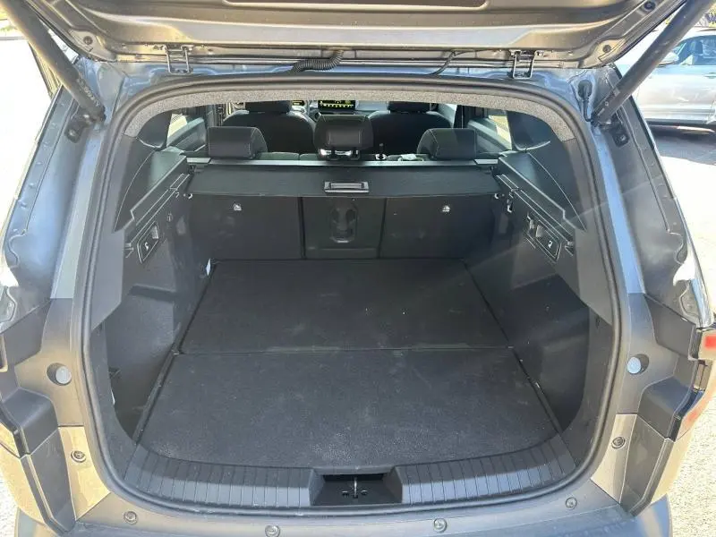 Coffre ouvert du Dacia Bigster gris schiste, vue arrière montrant l'espace de chargement et la banquette rabattable.