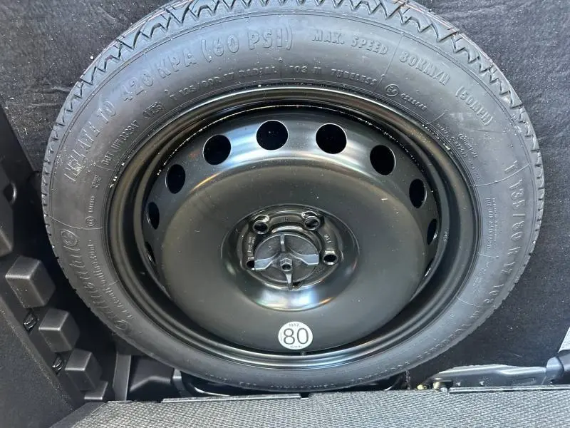 Gros plan sur la roue de secours noire du Dacia Bigster 2025, visible dans le coffre du véhicule gris schiste.