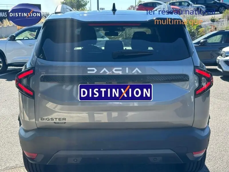 Vue arrière d'un Dacia Bigster gris schiste avec feux arrière LED en forme de C et logo DACIA lumineux.