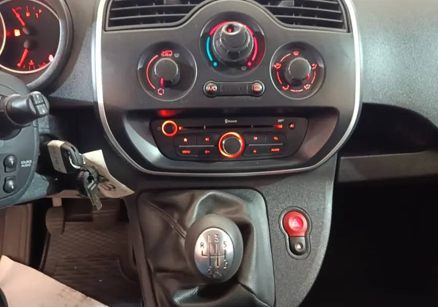 Vue rapprochée du tableau de bord et levier de vitesses manuel du Renault Kangoo 2020, commandes clim et audio visibles.