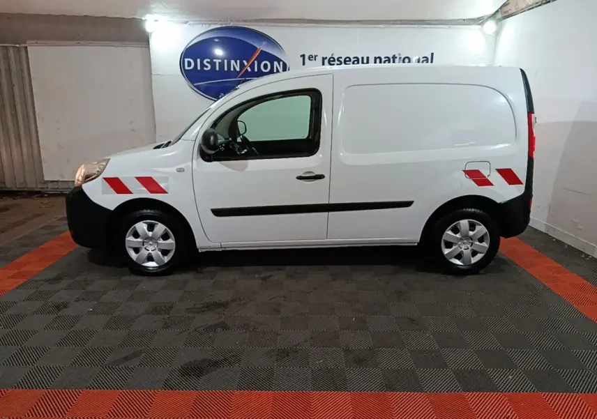 Vue de profil droit d’un Renault Kangoo blanc 2020 avec marquages rouges sur ailes avant et arrière dans un garage.