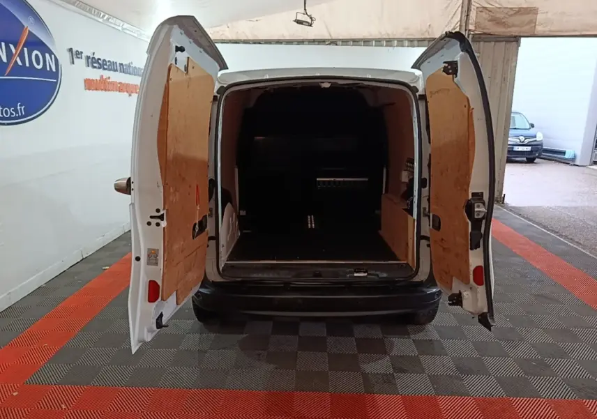 Vue arrière du Renault Kangoo blanc 2020 avec portes arrière ouvertes montrant l'espace de chargement vide et cloison bois.