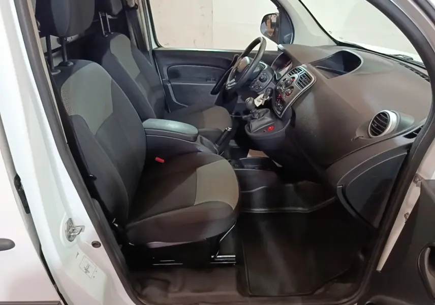 Vue intérieure côté conducteur du Renault Kangoo blanc 2020, montrant les sièges avant et le tableau de bord avec volant réglable.