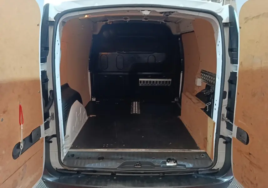 Vue arrière du Renault Kangoo blanc 2020 montrant l'espace de chargement avec cloison pleine et revêtement bois.
