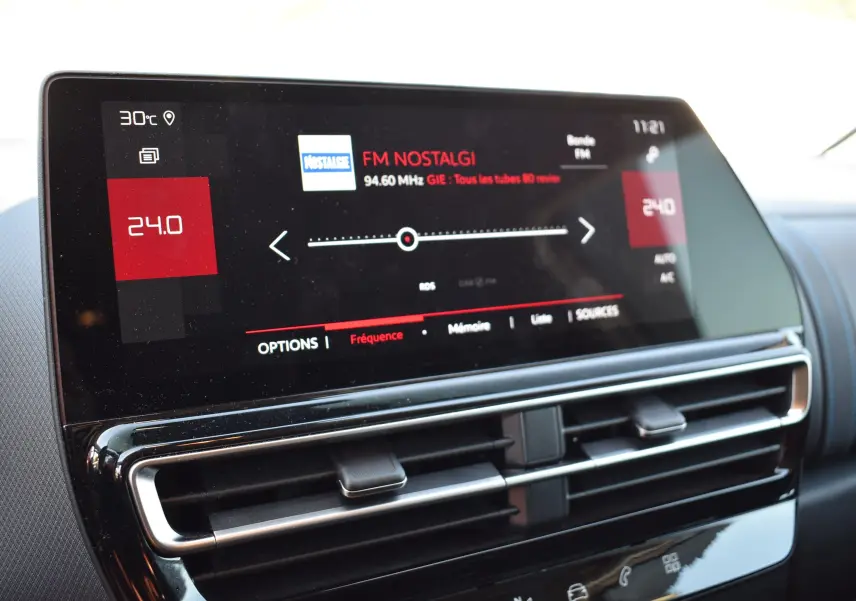 Écran tactile central du tableau de bord du Citroën C5 Aircross 2024 affichant la radio FM sur fond noir brillant.