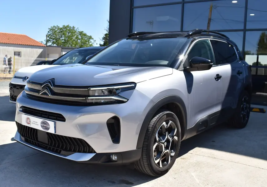 Citroën C5 Aircross 2024 gris métallisé vue 3/4 avant droit avec toit bi-ton noir et jantes distinctives.