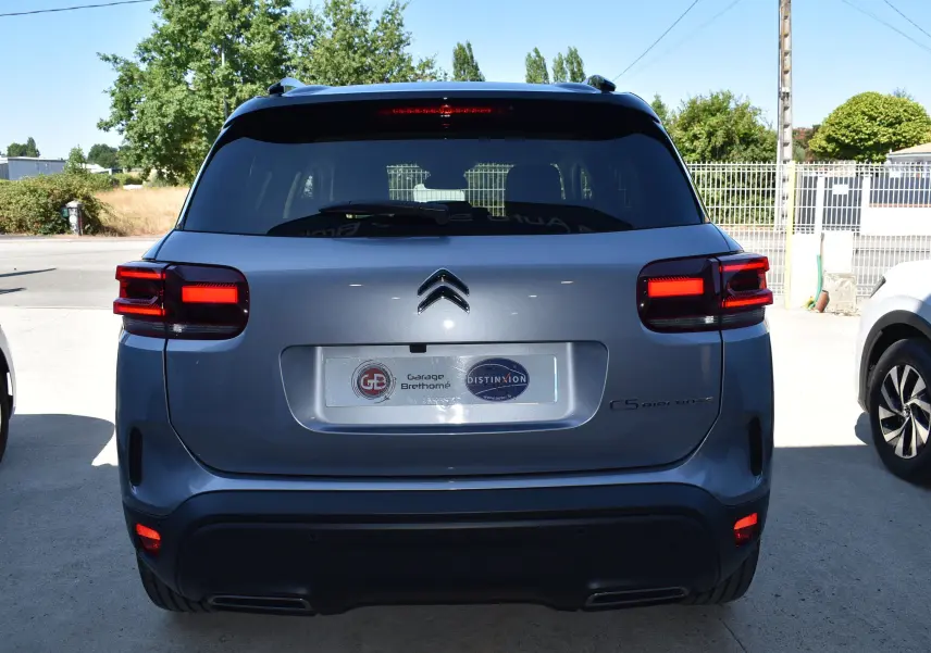 Vue arrière d'un Citroën C5 Aircross 2024 gris métallisé avec toit bi-ton noir et feux arrière allumés.