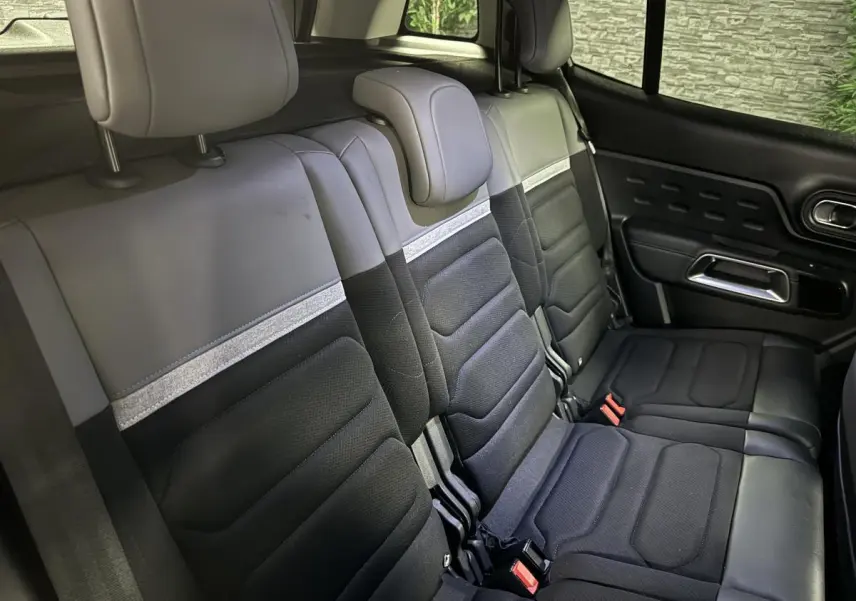 Vue intérieure des trois sièges arrière noirs et gris du Citroën C5 Aircross avec appuie-têtes et ceintures visibles côté droit.
