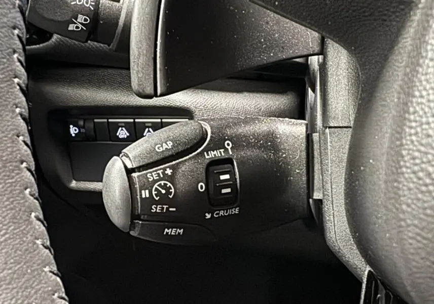 Gros plan sur la commande de régulateur de vitesse à gauche du volant du Citroën C5 Aircross noir 2022.