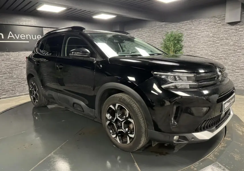 Citroën C5 Aircross noir perla Nera en 3/4 avant droit, avec jantes bi-ton et barres de toit noires brillantes.