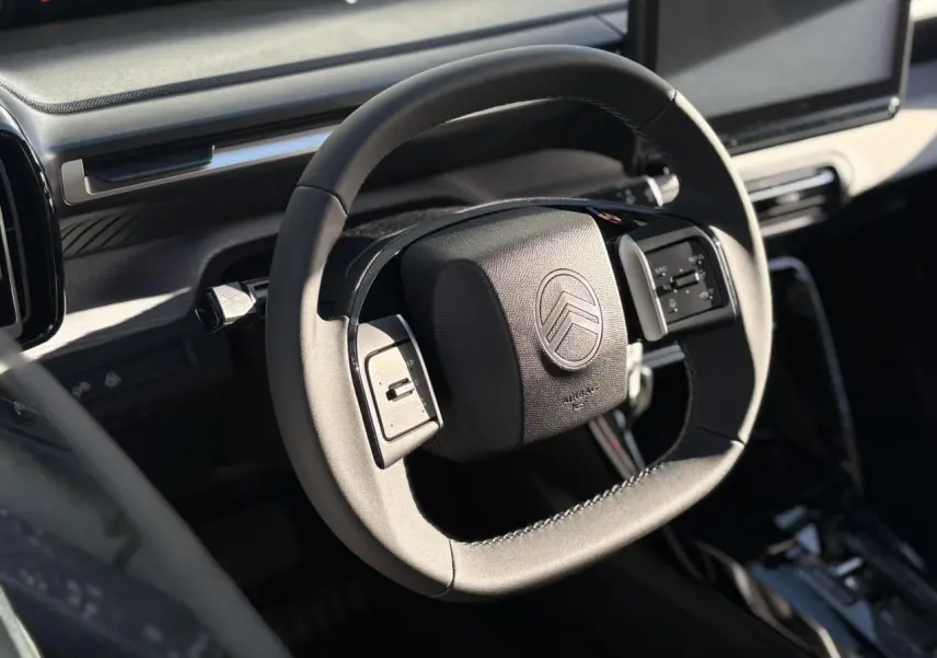 Vue rapprochée du volant multifonctions noir du Citroën C3 Aircross Hybrid 2025 avec tableau de bord gris sidérite.