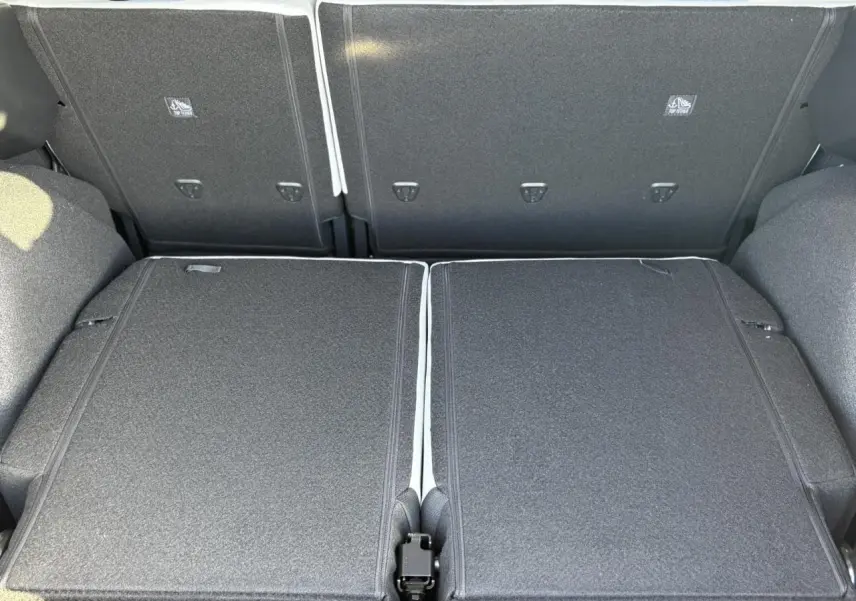 Vue rapprochée du coffre avec banquette arrière rabattue en tissu gris foncé du Citroën C3 Aircross Hybrid 2025.