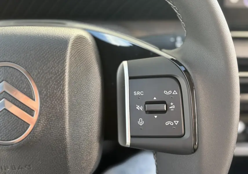 Gros plan sur les commandes multifonctions à droite du volant gris du Citroën C3 Aircross Hybrid 2025.