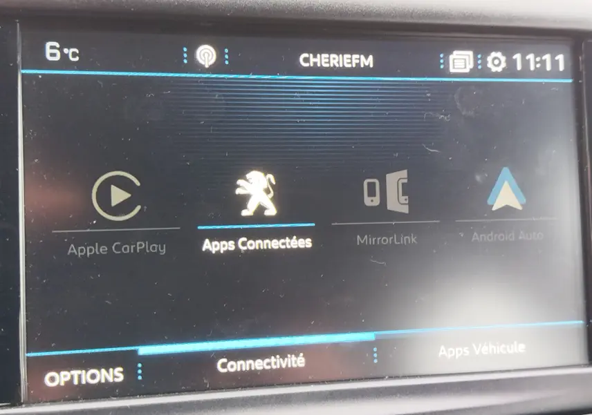 Écran tactile intérieur de la Peugeot 208 noir Perla Nera montrant les options de connectivité avec logo lion au centre.