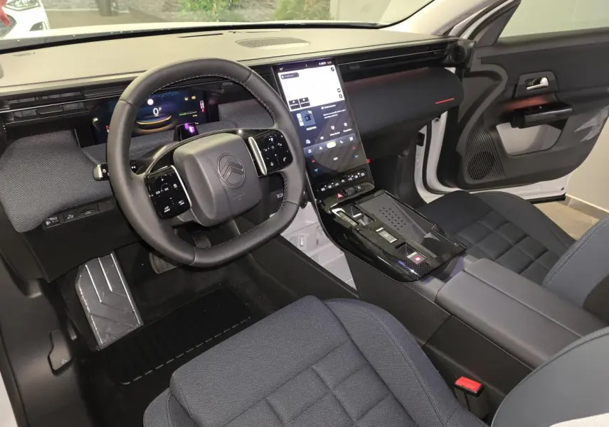 Vue intérieure avant droite du Citroën C5 Aircross 2026 avec tableau de bord numérique et sellerie tissu bleu.