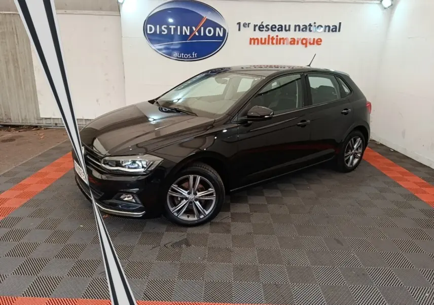 Volkswagen Polo noire 2020 vue 3/4 avant droit en intérieur avec jantes alliage et phares LED allumés.