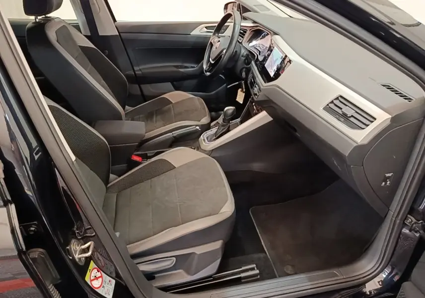 Vue intérieure côté conducteur de la Volkswagen Polo noire 2020, montrant sièges et tableau de bord moderne.