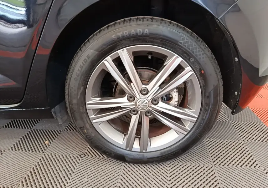 Gros plan sur la roue avant gauche avec jante alliage argentée d'une Volkswagen Polo noire 2020.
