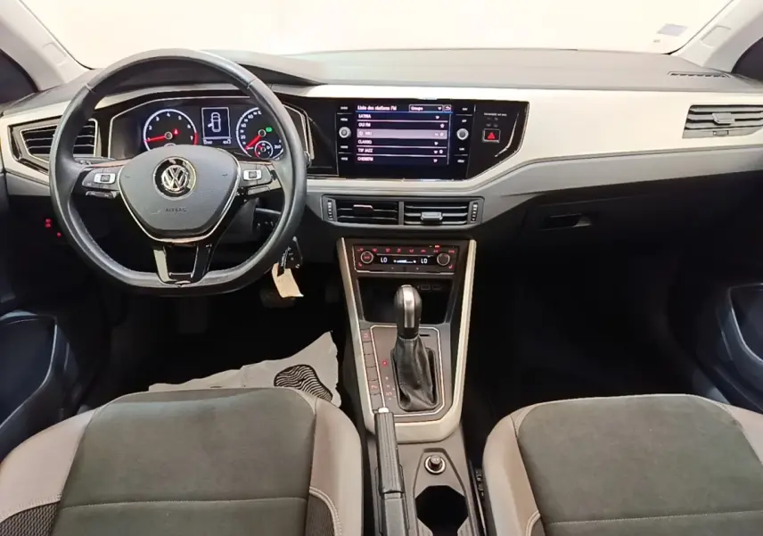 Vue intérieure avant de la Volkswagen Polo noire, tableau de bord moderne avec écran tactile central et volant multifonctions.
