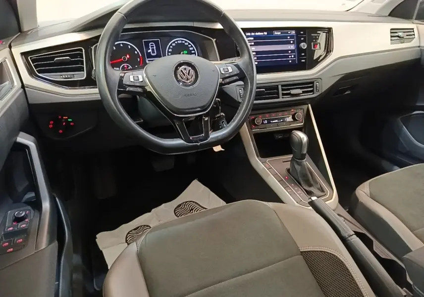 Vue intérieure avant de la Volkswagen Polo noire 2020, tableau de bord avec écran tactile et volant multifonctions en cuir.