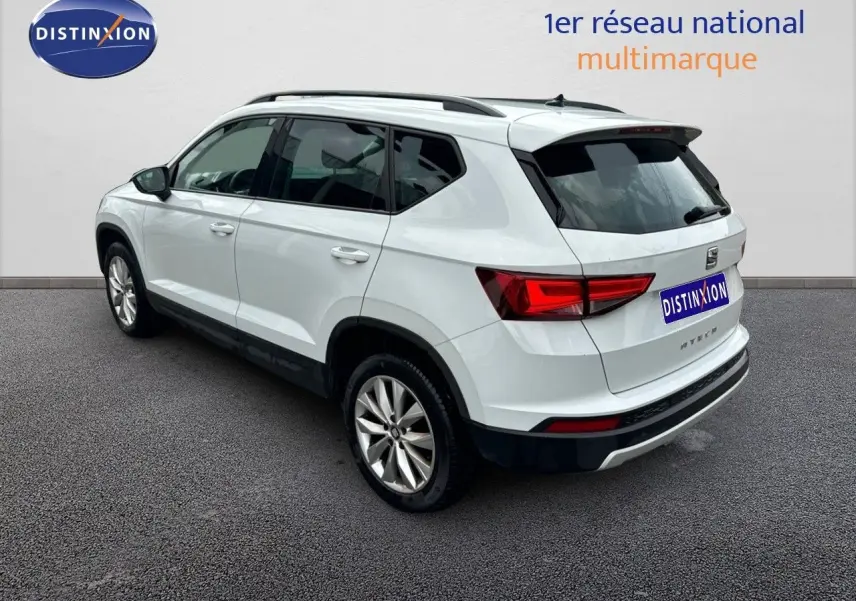 Vue 3/4 arrière droite d'un SUV SEAT Ateca blanc de 2018 avec jantes alliage et barres de toit noires.