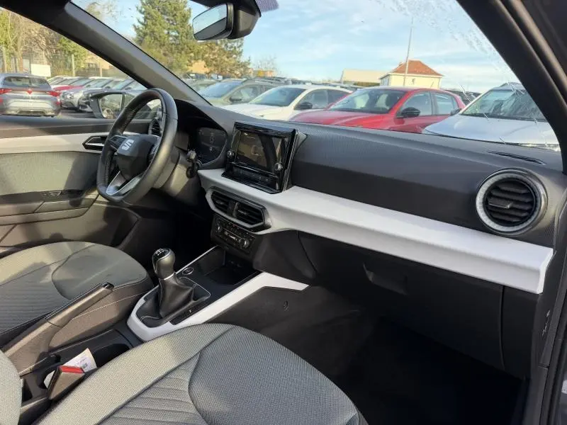 Vue intérieure côté conducteur de la SEAT Ibiza 2025, montrant le tableau de bord et la boîte manuelle, ambiance grise et moderne.