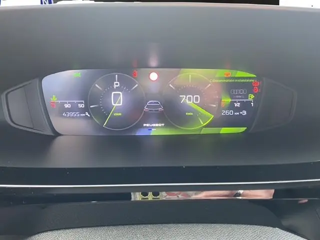 Vue rapprochée du tableau de bord numérique du Peugeot 308 SW 2022, affichant la vitesse, la consommation et les alertes.