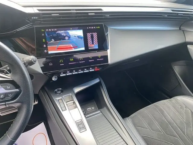 Vue intérieure côté passager du tableau de bord et console centrale de la Peugeot 308 SW blanche nacrée avec écran tactile affichant la caméra de recul.