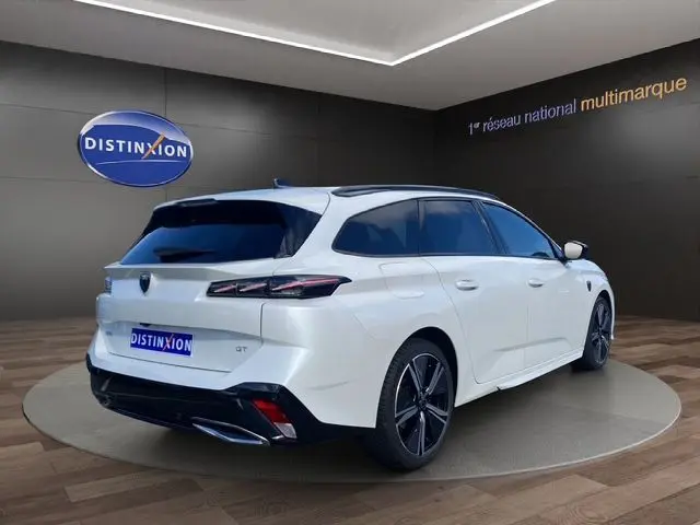 Peugeot 308 SW blanc nacré vue 3/4 arrière droit, avec jantes noires et feux arrière LED distinctifs.