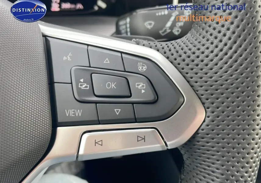 Gros plan sur les commandes multifonctions en cuir perforé du volant côté gauche de la Volkswagen Golf noire 2026.