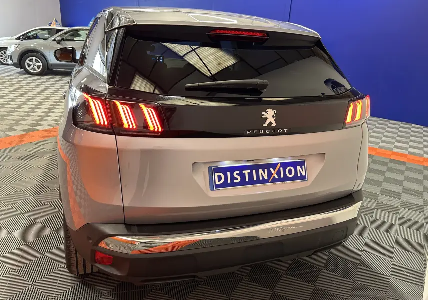 Vue 3/4 arrière droite d’un Peugeot 3008 gris avec feux arrière allumés et plaque d’immatriculation Distinxion.