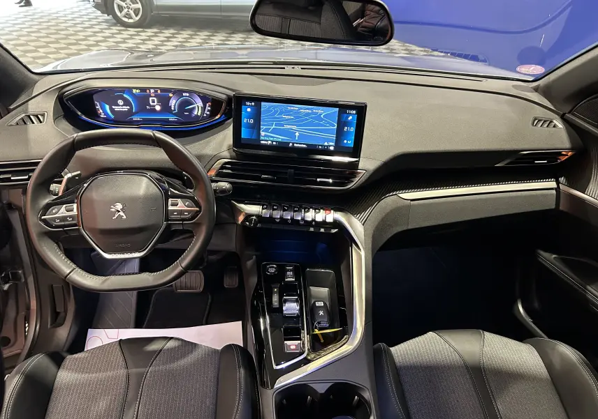 Vue intérieure avant du Peugeot 3008 Hybrid gris 2024, avec tableau de bord numérique et écran tactile GPS central.