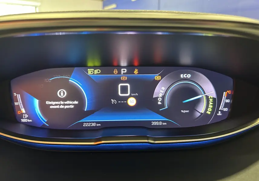 Tableau de bord numérique du Peugeot 3008 Hybrid 2024 affichant la vitesse à 0 km/h et l'indicateur de charge hybride.