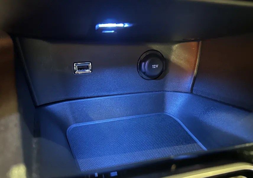 Détail de la console centrale du Peugeot 3008 Hybrid gris, montrant une prise USB et une prise 12V éclairées en bleu.